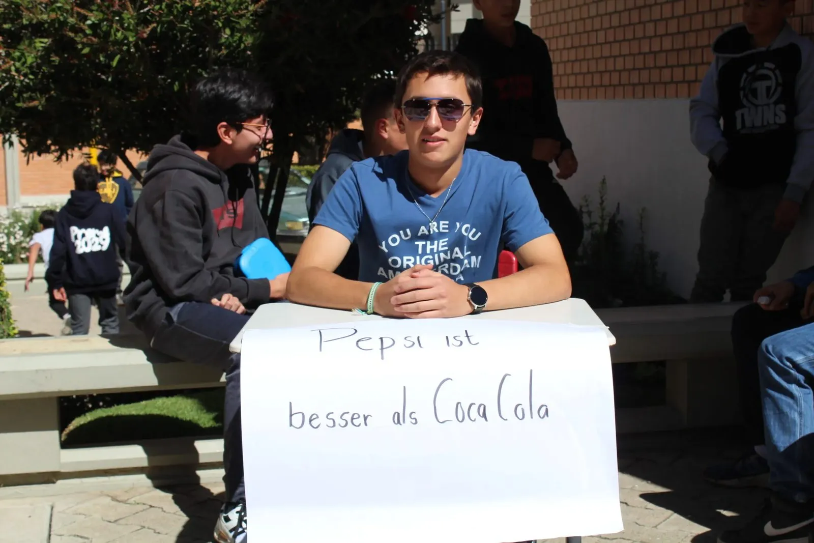 Schüler verteidigt die These »Pepsi ist besser als Coca-Cola« an seinem Tisch auf dem Pausenhof.